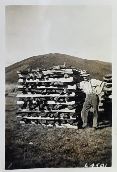 Man leaning against a seasoning woodpile
