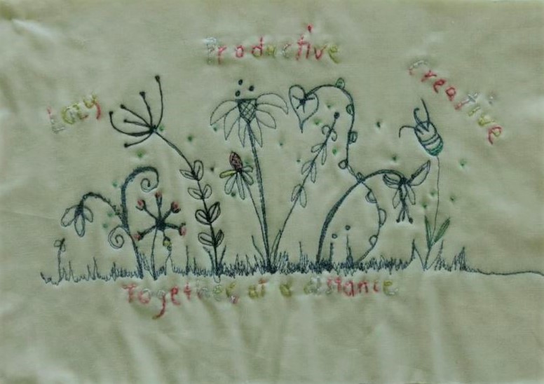 Embroidered quilt piece with flowers and the words lazy, productive, creative, together at a distance