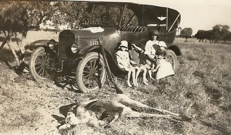 Family with car, gun, and dead kangaroo