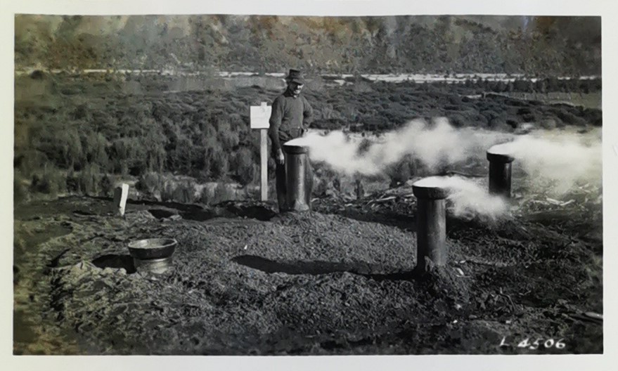 Man standing by a charcoal pit 