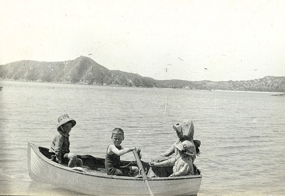 Child rowing a dinghy with adult and child