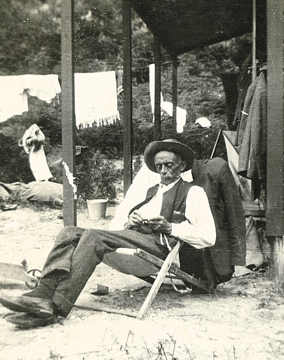 Elderly man sitting on deck chair at the bach