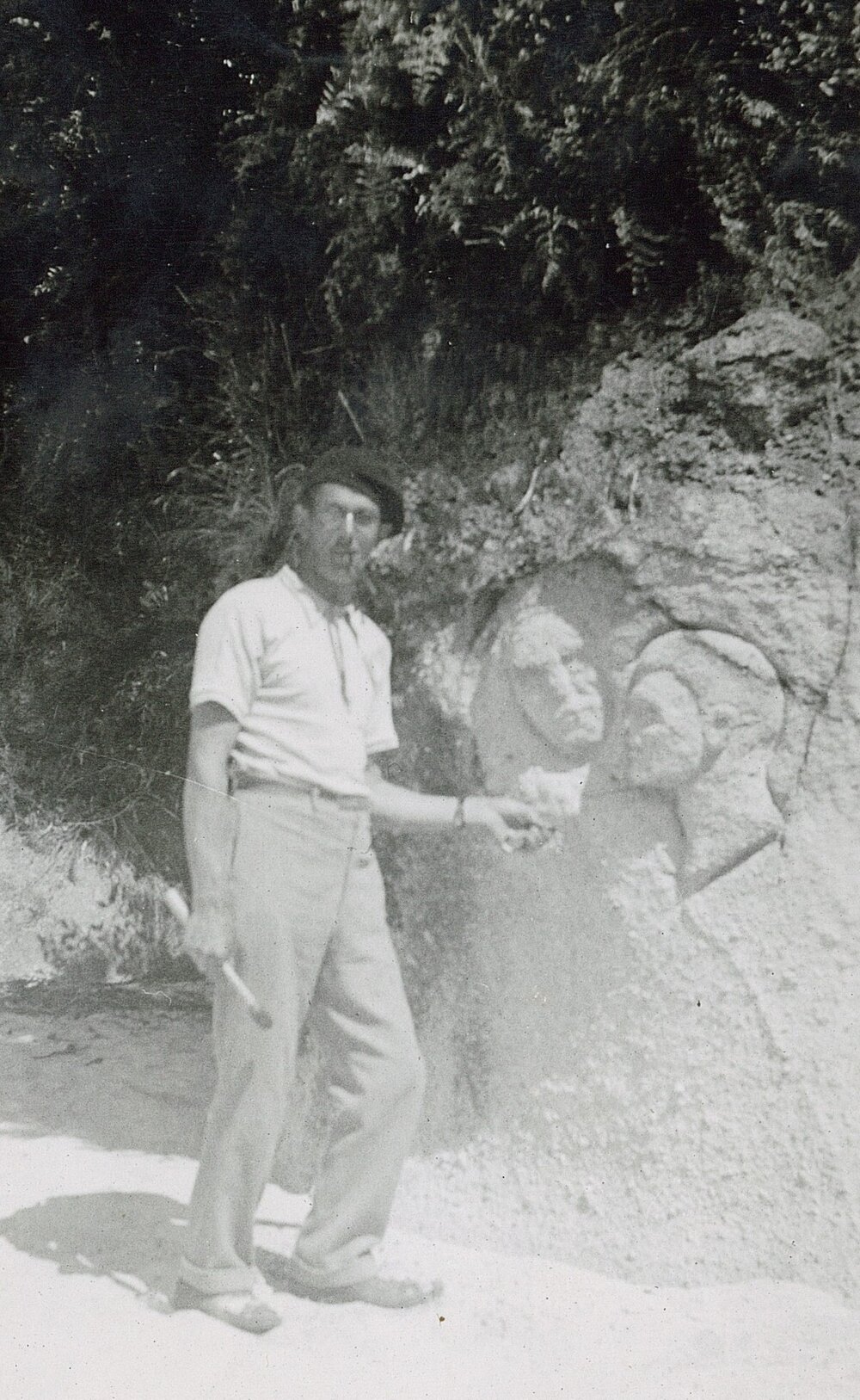 Man carving faces into rock on the beach