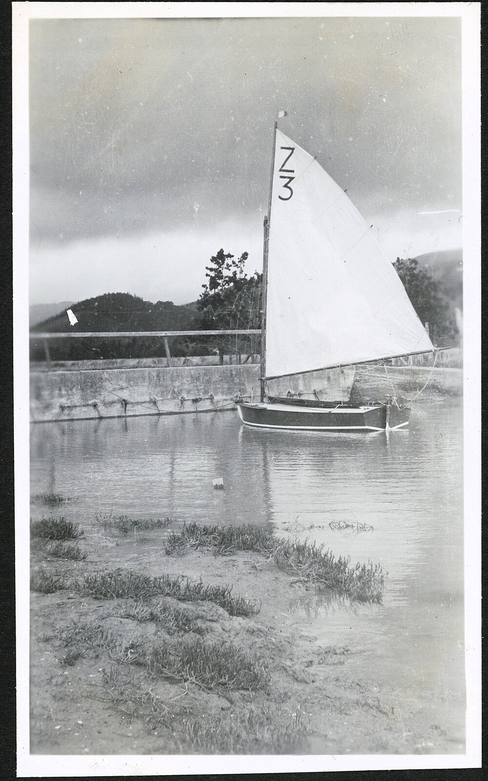 Small sailboat in front of a concrete structure