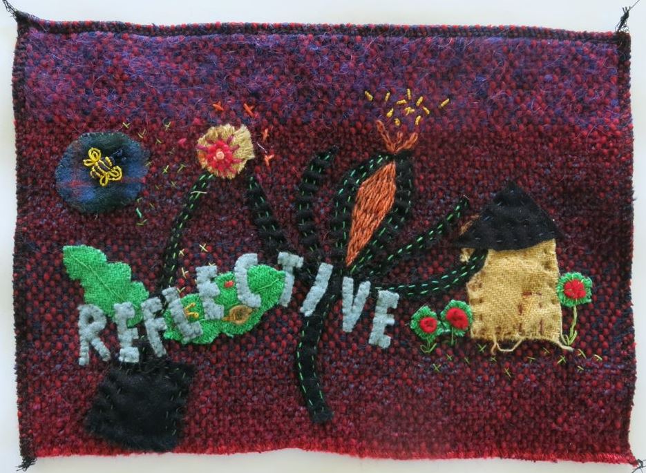 Knitted quilt piece appliqued with flowers and the word reflective