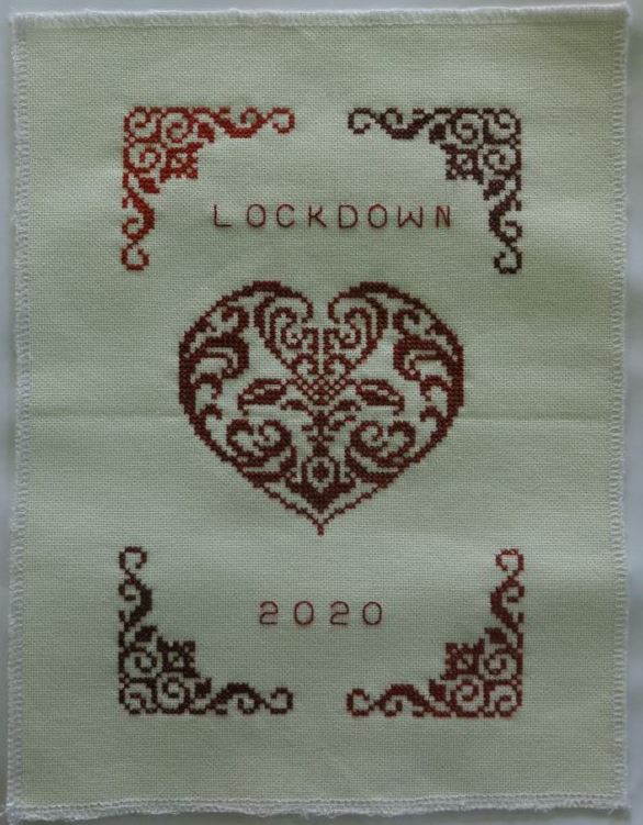 Cross stitch quilt piece with a heart, corner scrolls and the words Lockdown 2020
