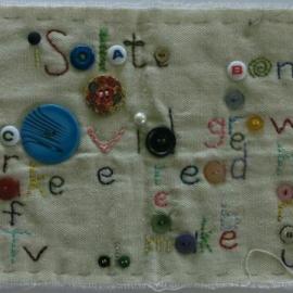 Quilt square embroidered with lock-down related words and buttons in crossword