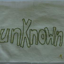 White fabric quilt square embroidered with the word unknown