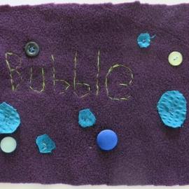 Fleece quilt piece with the word bubble embroidered and blue buttons