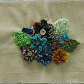 Fabric quilt square with knitted flowers and leaves in a posy