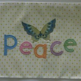 Quilt square appliqued with a butterfly and the word peace