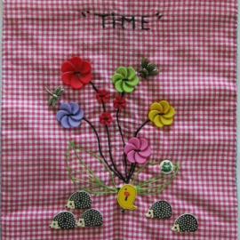 Red quilt piece embroidered with flowers made of buttons and the word time