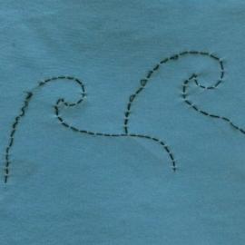 Blue fabric quilt piece embroidered with two koru