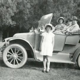 Three unknown women and a girl, with car