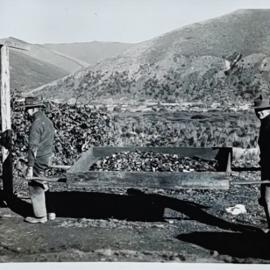 Two men carrying charcoal in a wooden carrier 