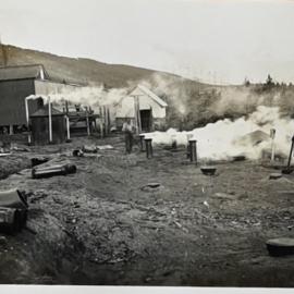 Man with brush next to smoking chimneys