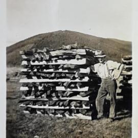 Man leaning against a seasoning woodpile