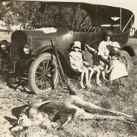 Family with car, gun, and dead kangaroo