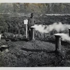 Man standing by a charcoal pit 