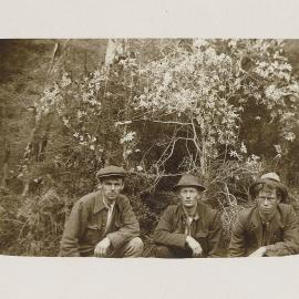 Three men in front of flowering plant