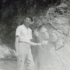 Man carving faces into rock on the beach