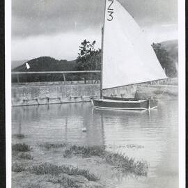Small sailboat in front of a concrete structure